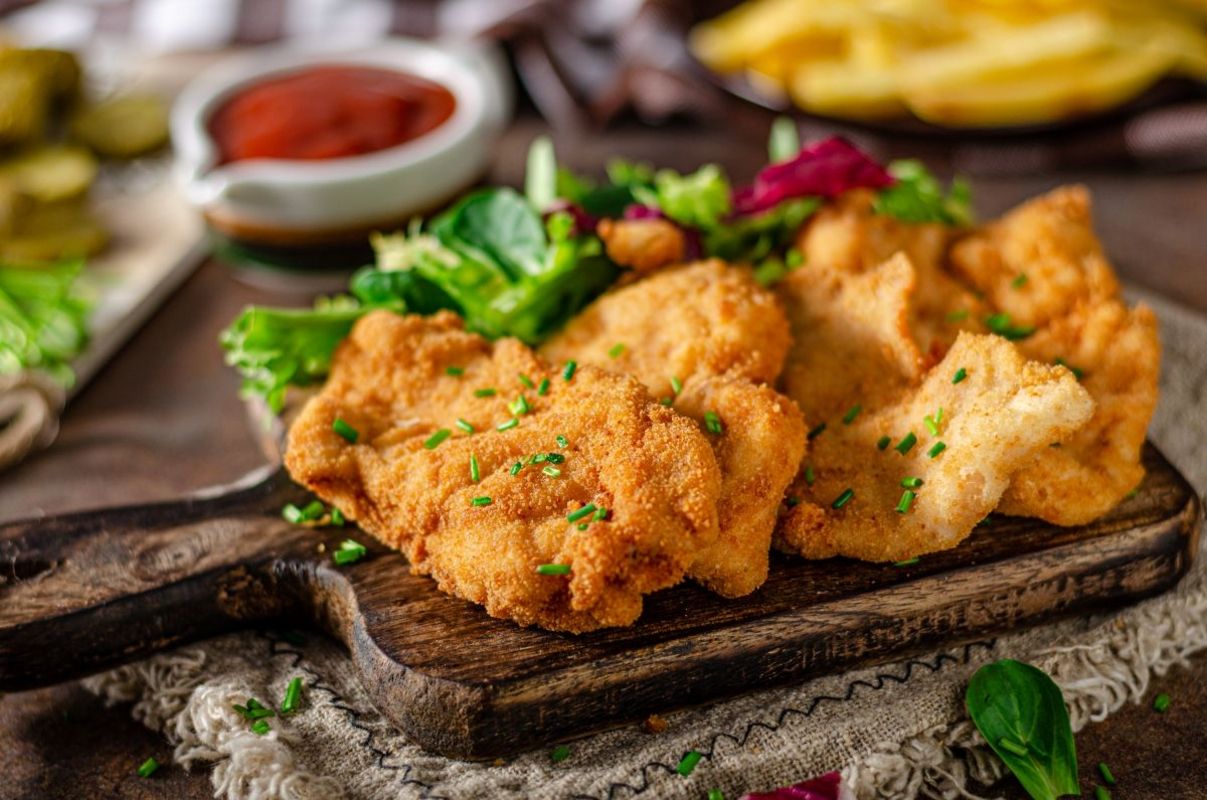 Vier Schnitzel auf einem Brett mit Salat